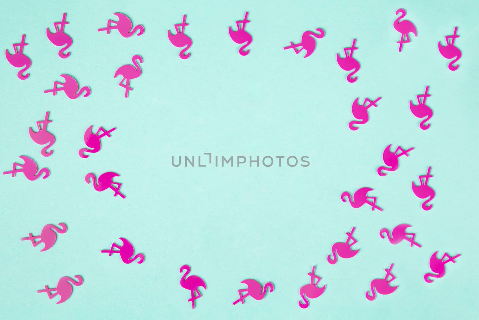 Summer tropical background, frame of chaotic pattern made of numerous pink flamingo confetti on turquoise pastel background, flatly, copy space. Summertime, relax, joy, pool party concept. Horizontal.