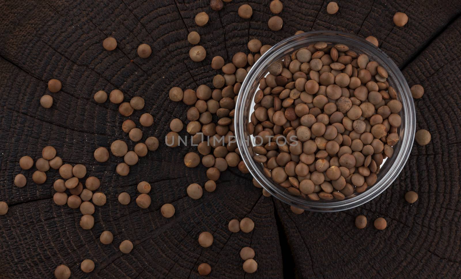 Bowl of lentils on black wooden background, top view