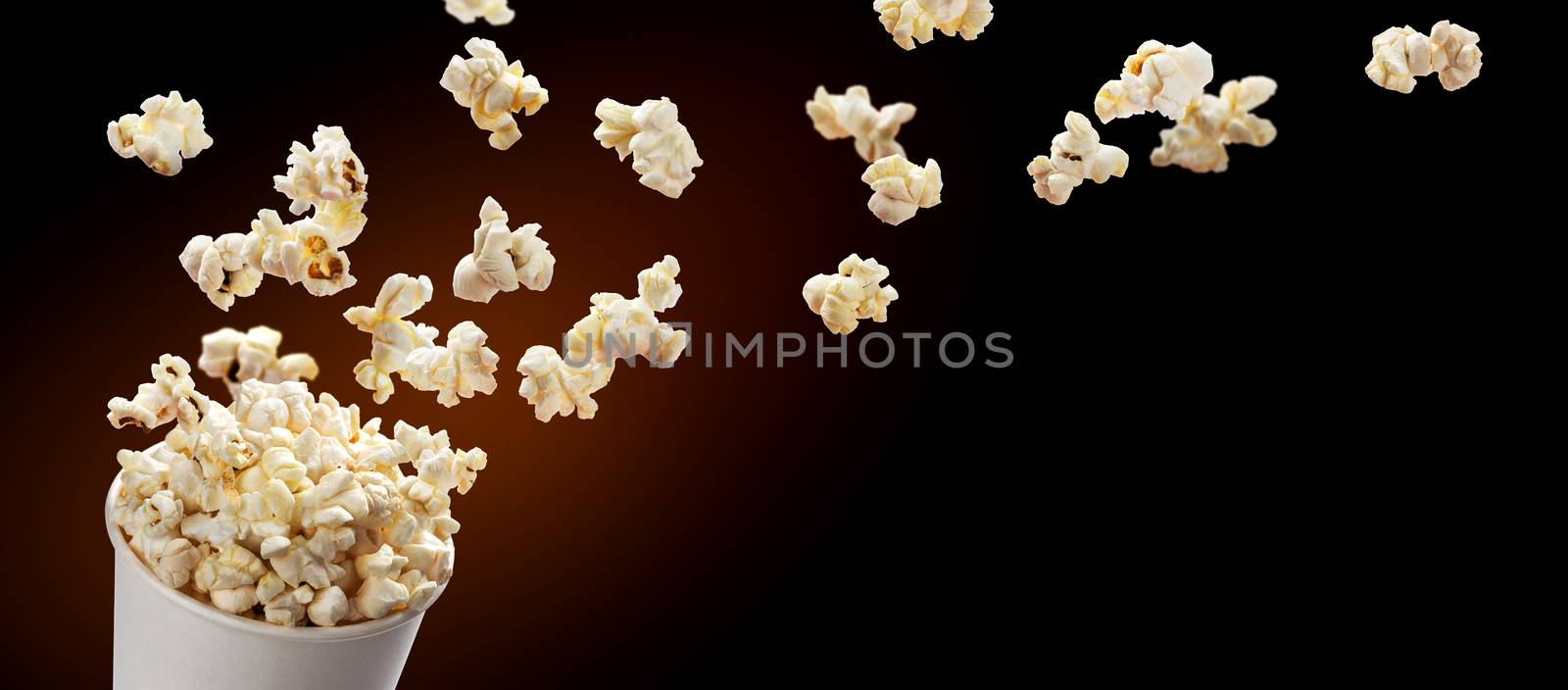 Popcorn flying out of cardboard box. Isolated on black background with copy space