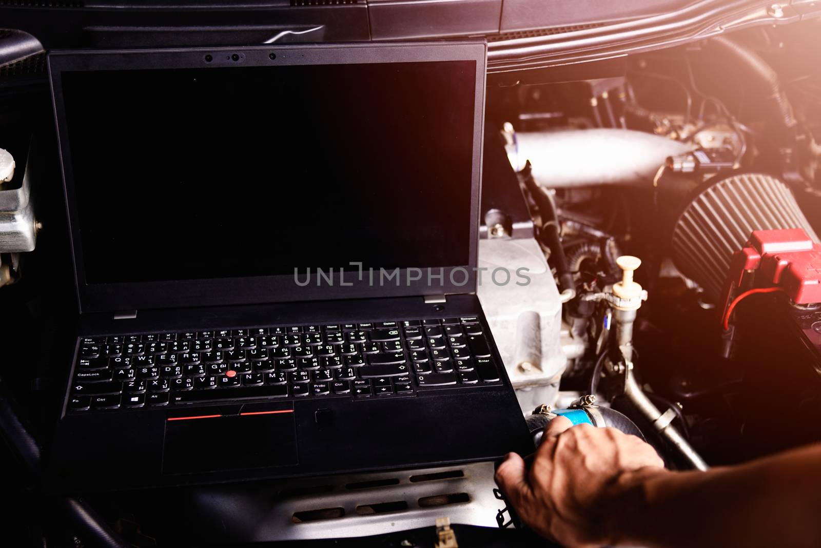 Professional car repair or maintenance mechanic engine working service with laptop computer at workshop