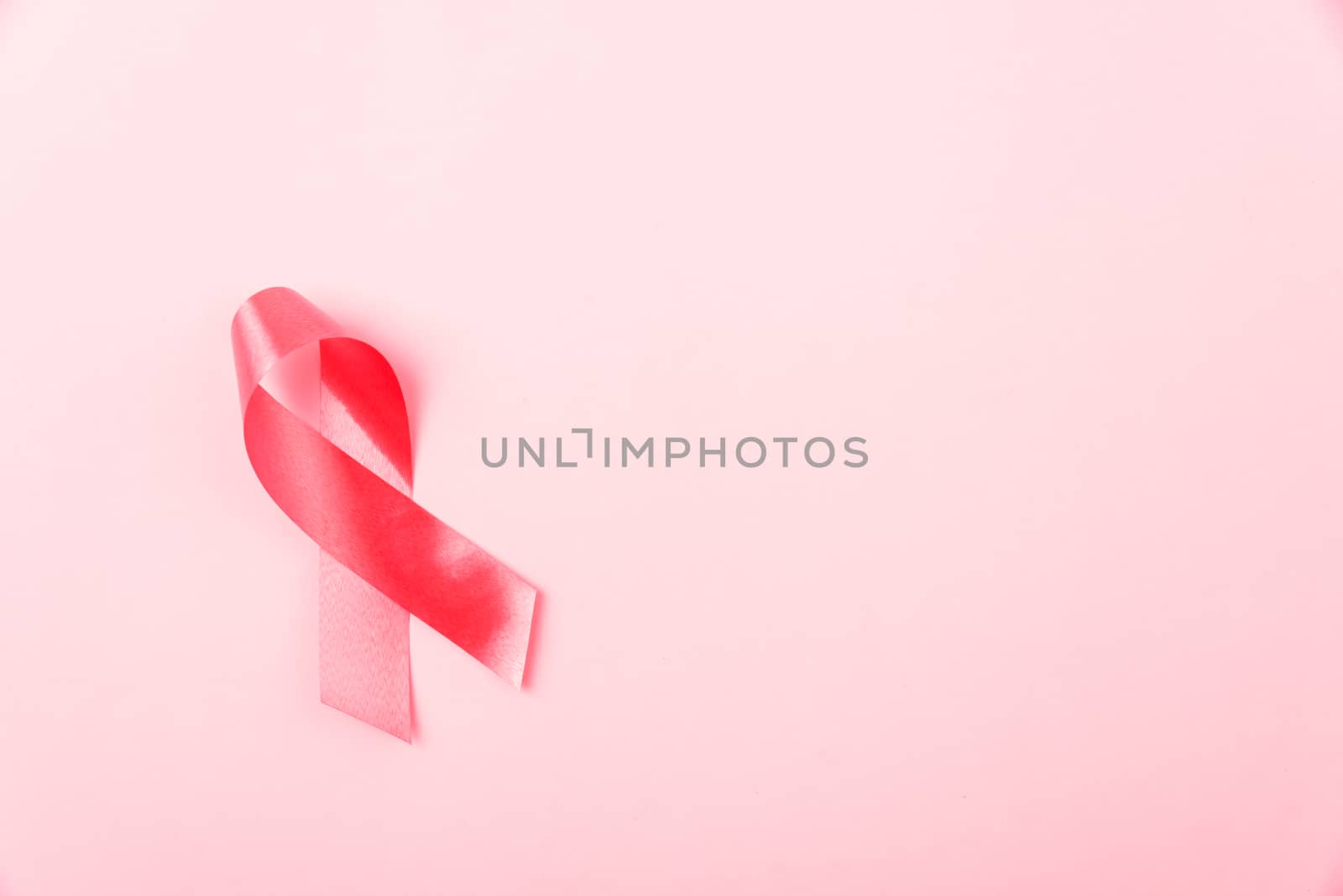 Breast Cancer Awareness Month concept, top view flat lay pink ribbon on pink background with copy space for your text