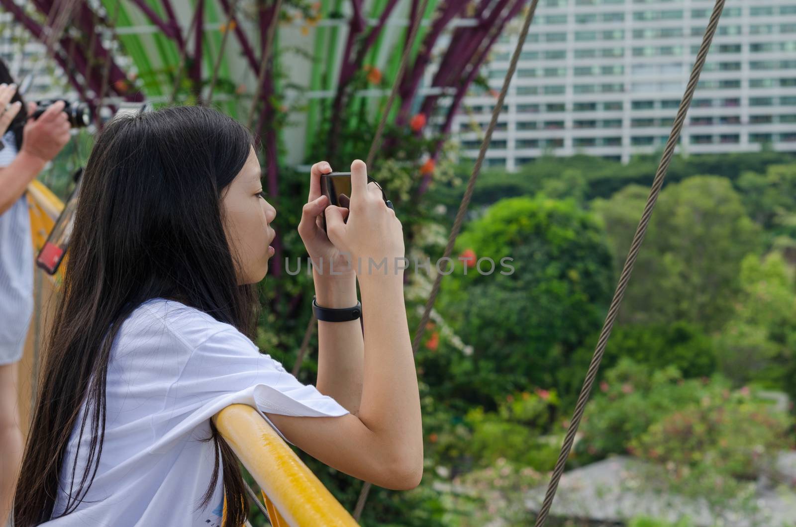 A young girl is using a mobile phone to take pictures at Gardens by the Bay, Singapore.