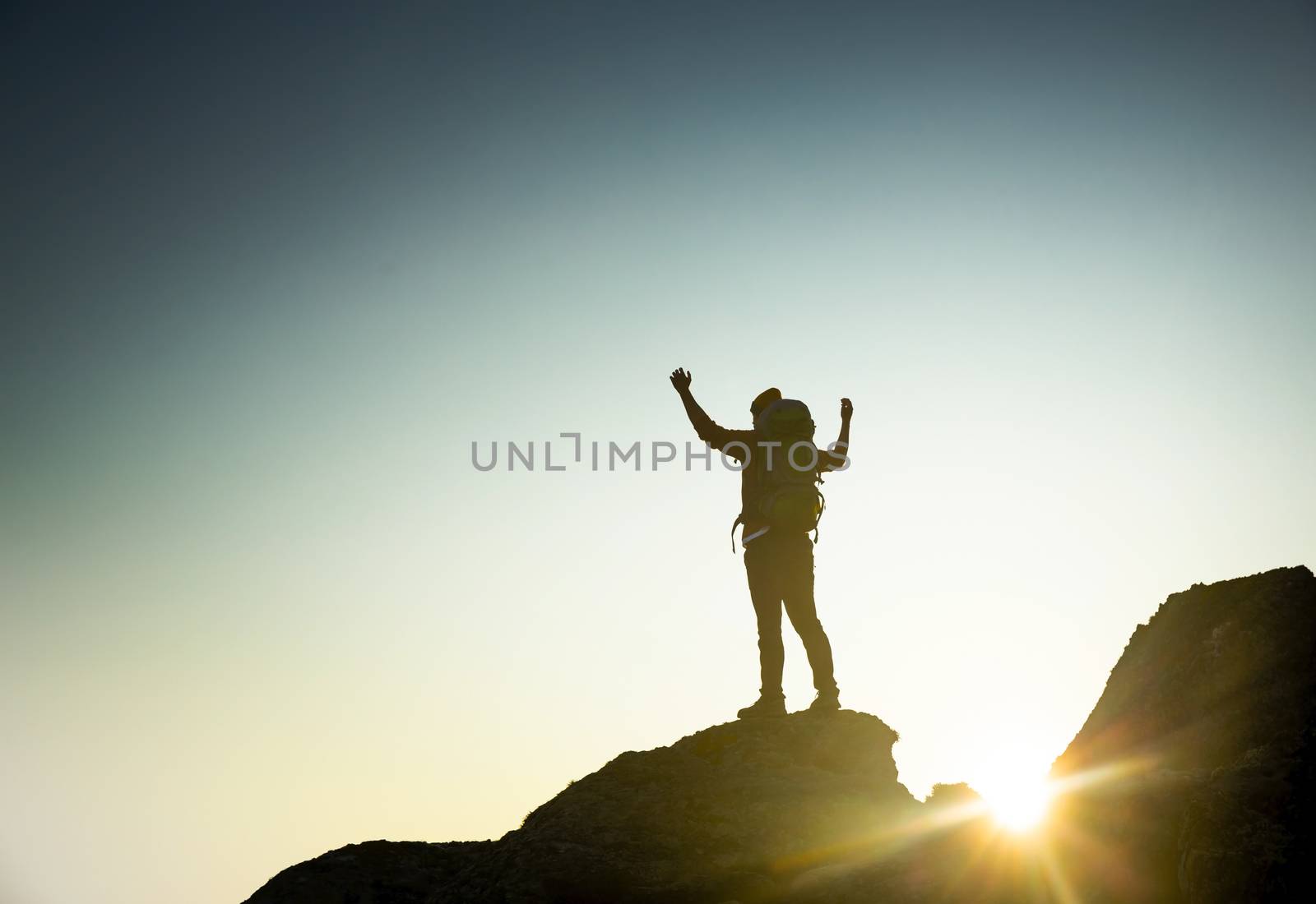 Shot of a man with arms raised and enjoying the of the montains at sunset