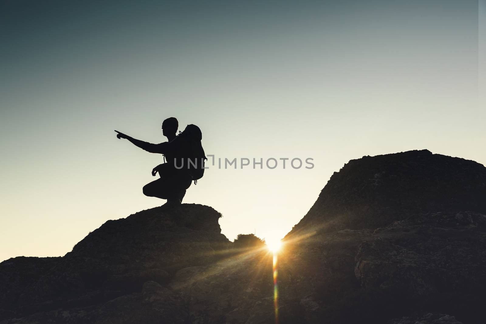 Shot of a man pointing to the view of the montains at sunset