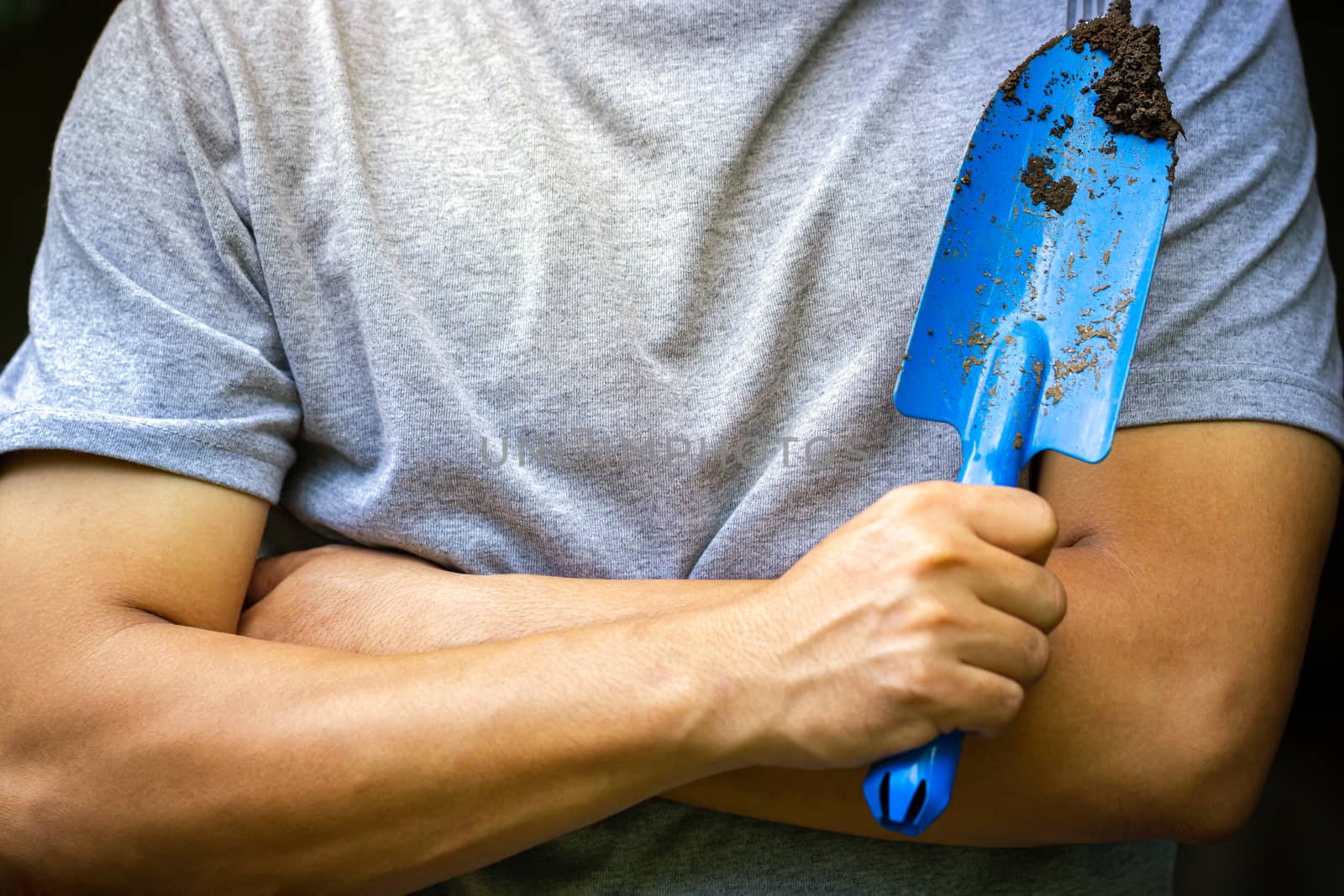 Gardener holding garden trowel and cross one's arm. Concept of agriculture. Closeup and copy space for text.