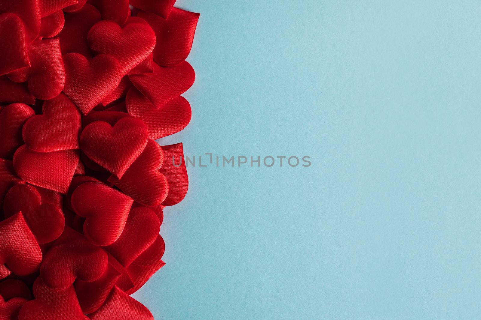 Valentine's day many red silk hearts on blue paper background , border frame on red with copy space, love concept