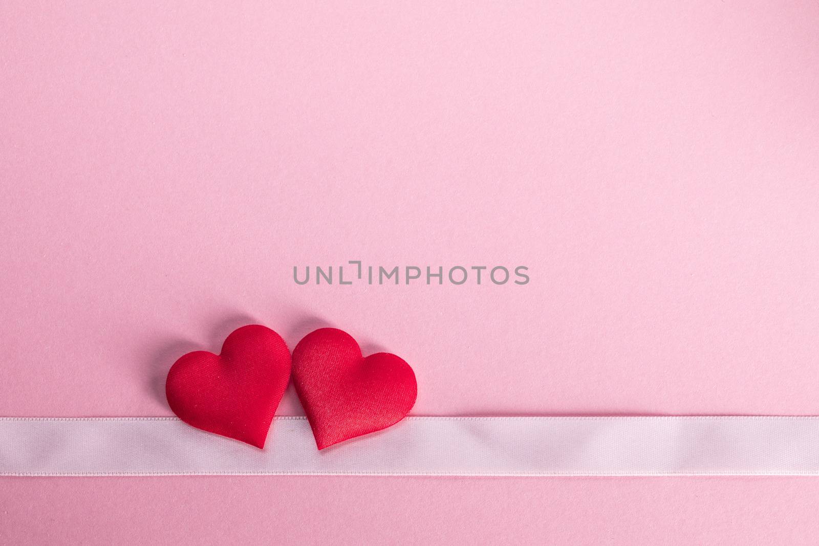 Valentine's day two red silk hearts and ribbon stripe on pink background, love concept