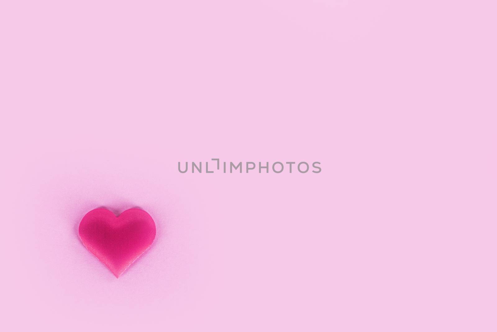 Valentine's day silk heart on pink paper background, love concept