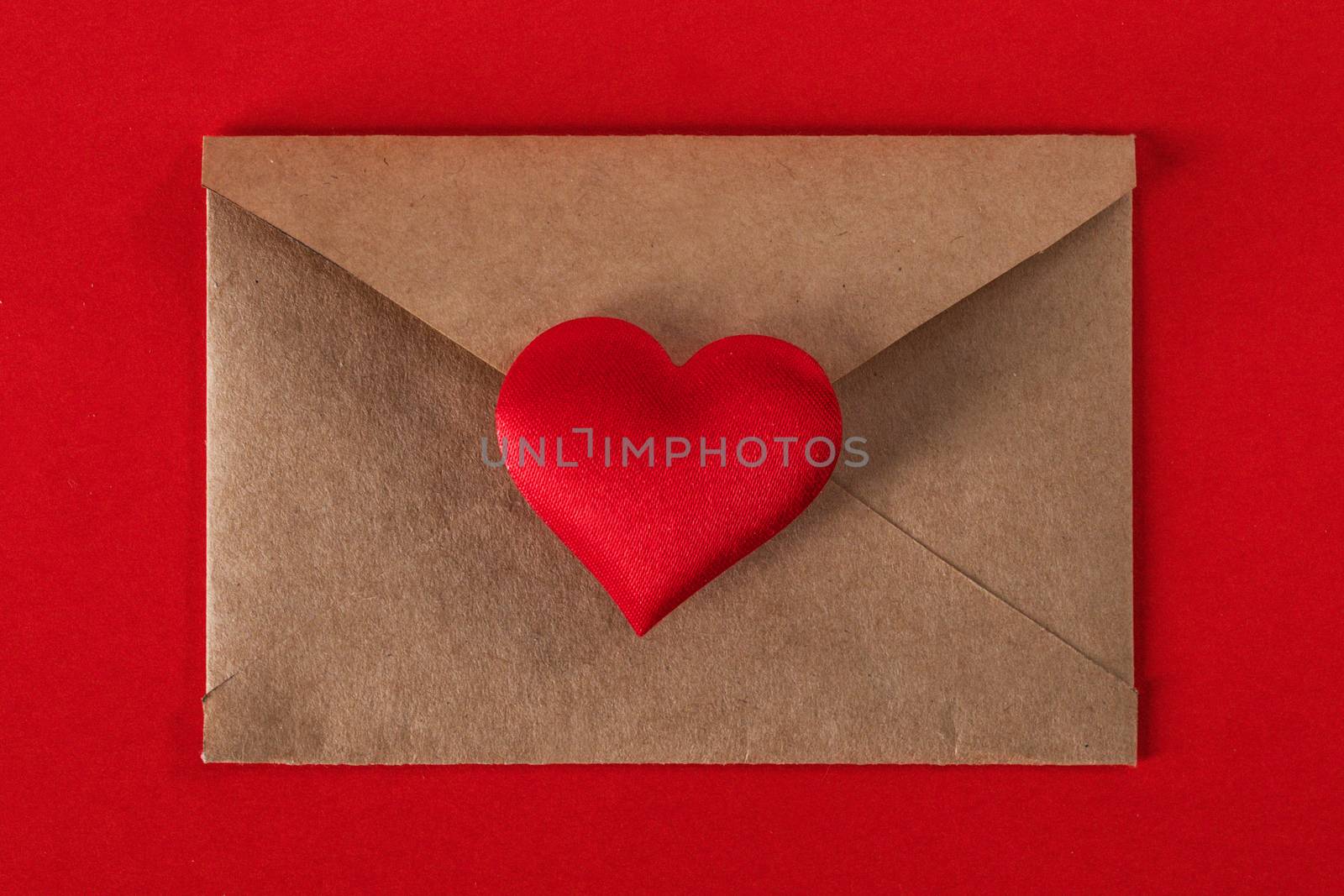 Valentine day love letter, envelope of craft paper with red heart on red background