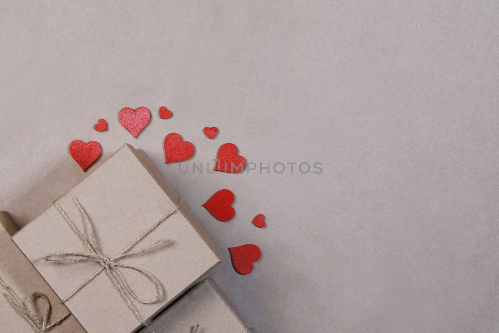 Box with gifts wrapped in brown craft paper and red paper hearts Valentines day concept