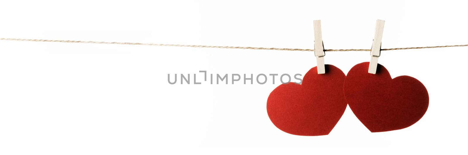 Clothes pegs and two red paper hearts on rope isolated on white background Valentines day concept