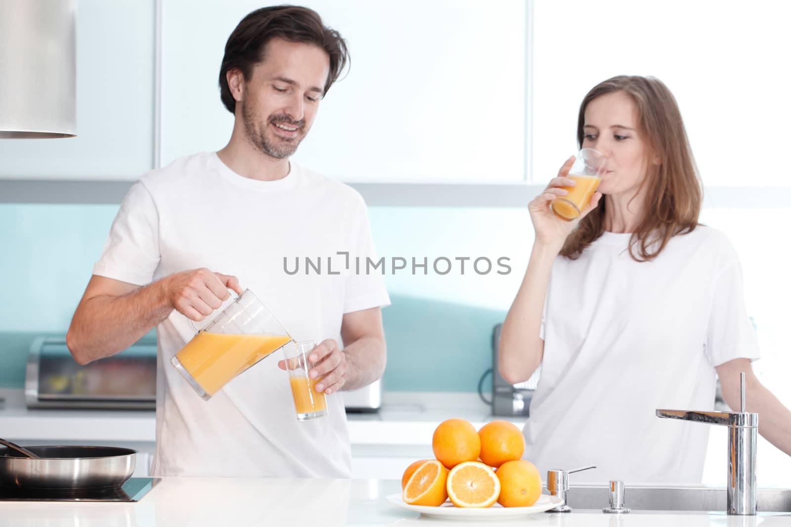 Couple with orange juice in the kitchen