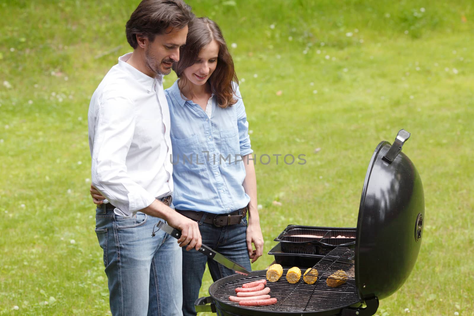 Happy couple cooking food on barbecue