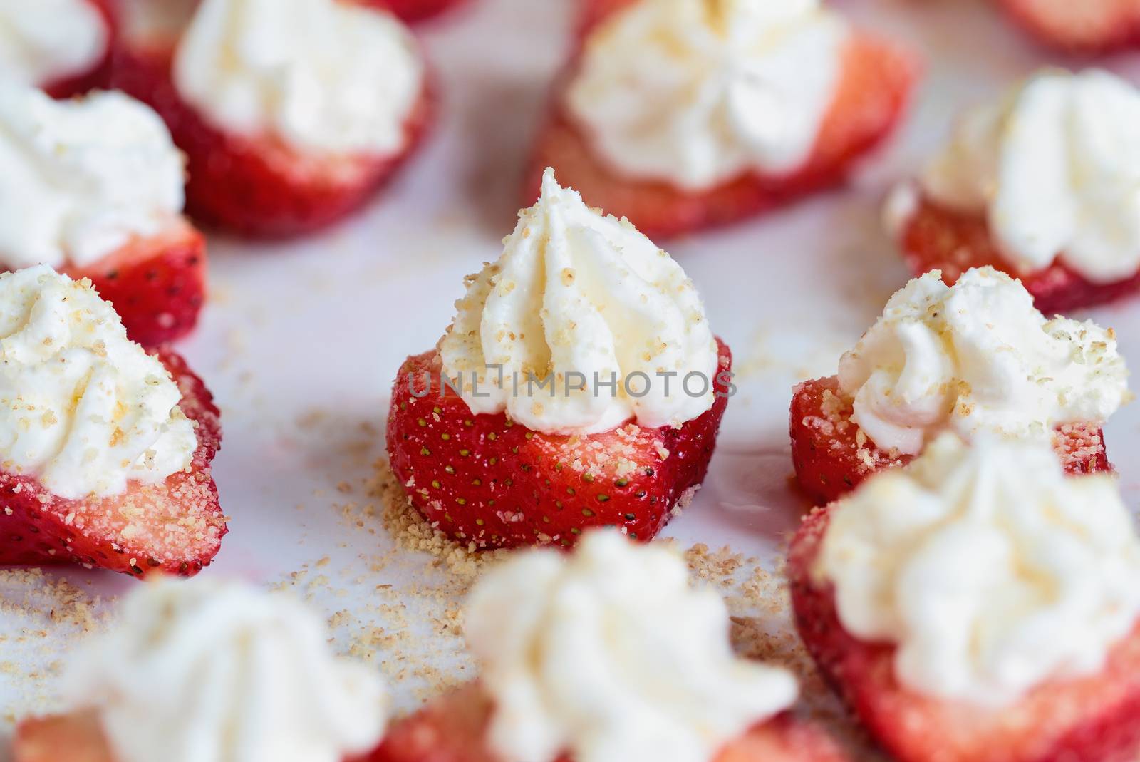 Fresh homemade stuffed deviled strawberries for the holidays. Berries are filled with cheesecake filling made with whipped cream and cream cheese and sprinkled with graham cracker crumbs. Selective focus with blurred foreground and background.