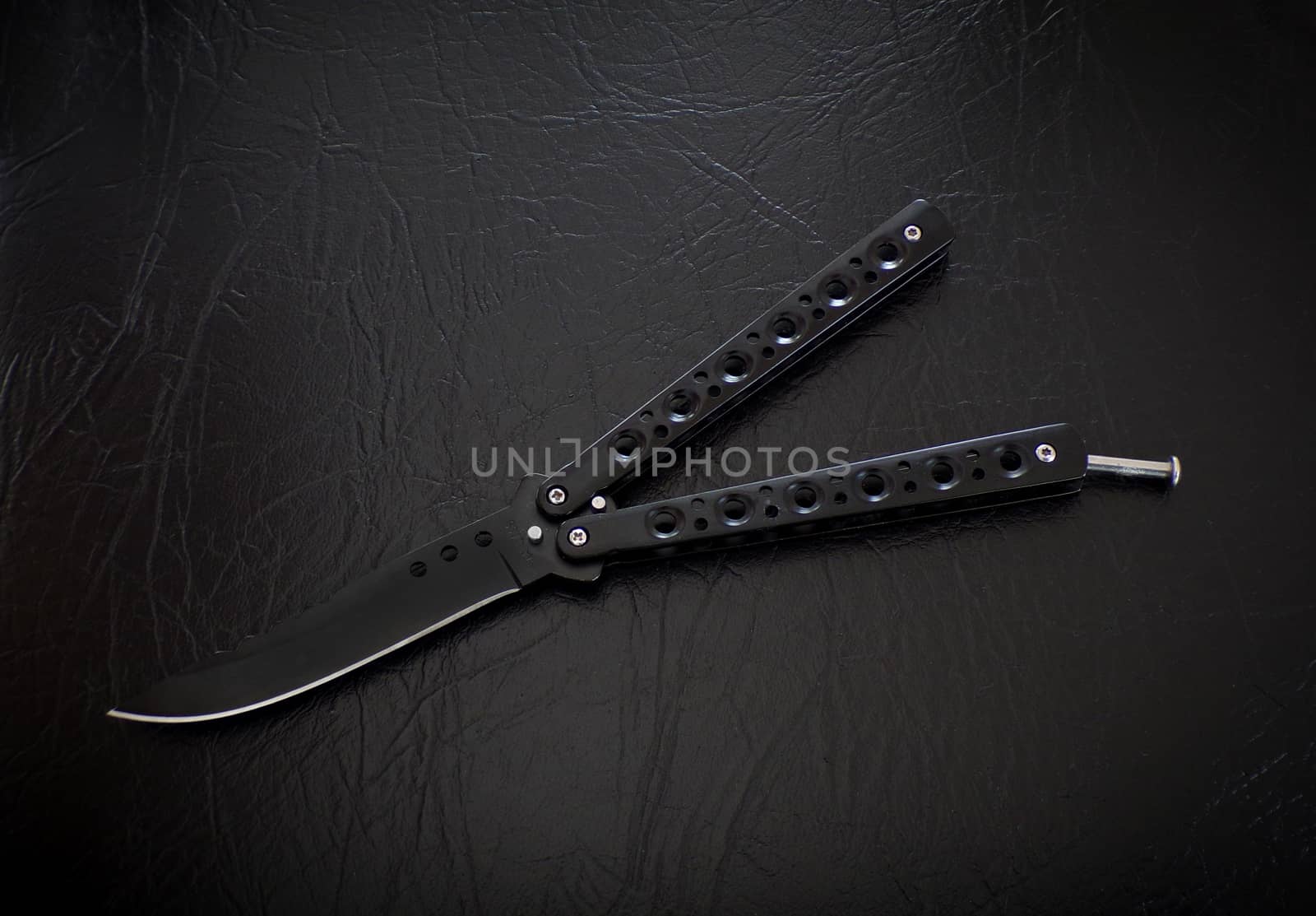 Butterfly knife on a black leather background. Balisong knife.