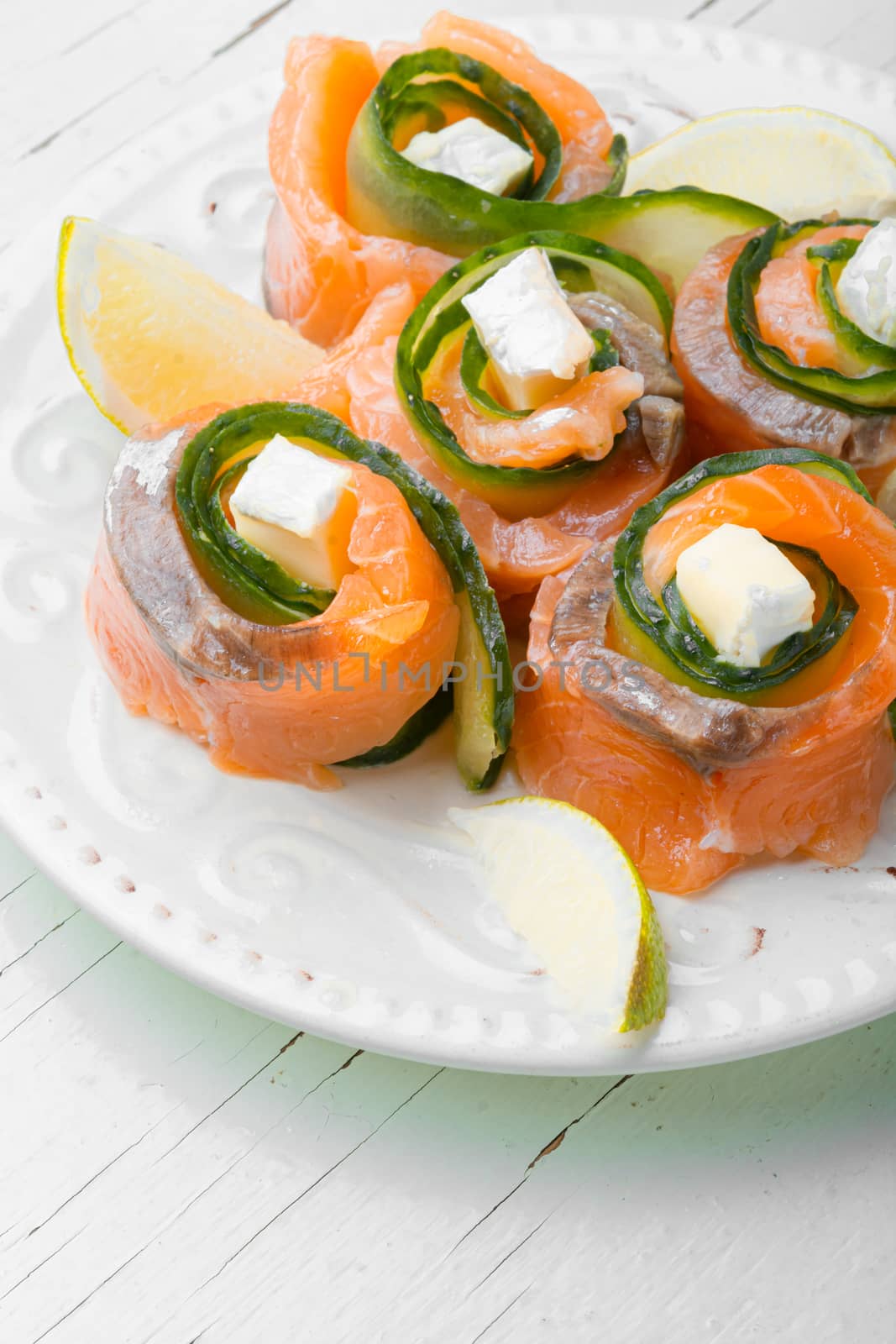 Salmon roll with cheese,cucumber and lime on plate.Rolls of red fish fillet