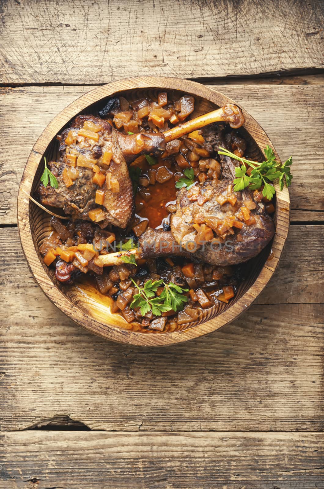 Duck legs baked with apple sauce in a wooden plate