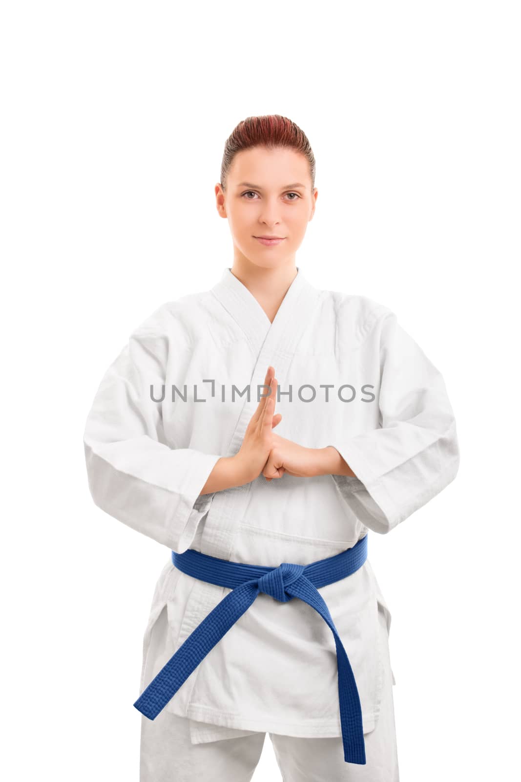 Portrait of a beautiful female martial arts fighter in a white kimono with blue belt performing a hand salute, isolated on white background. Girl in a kimono performing a hand salute.