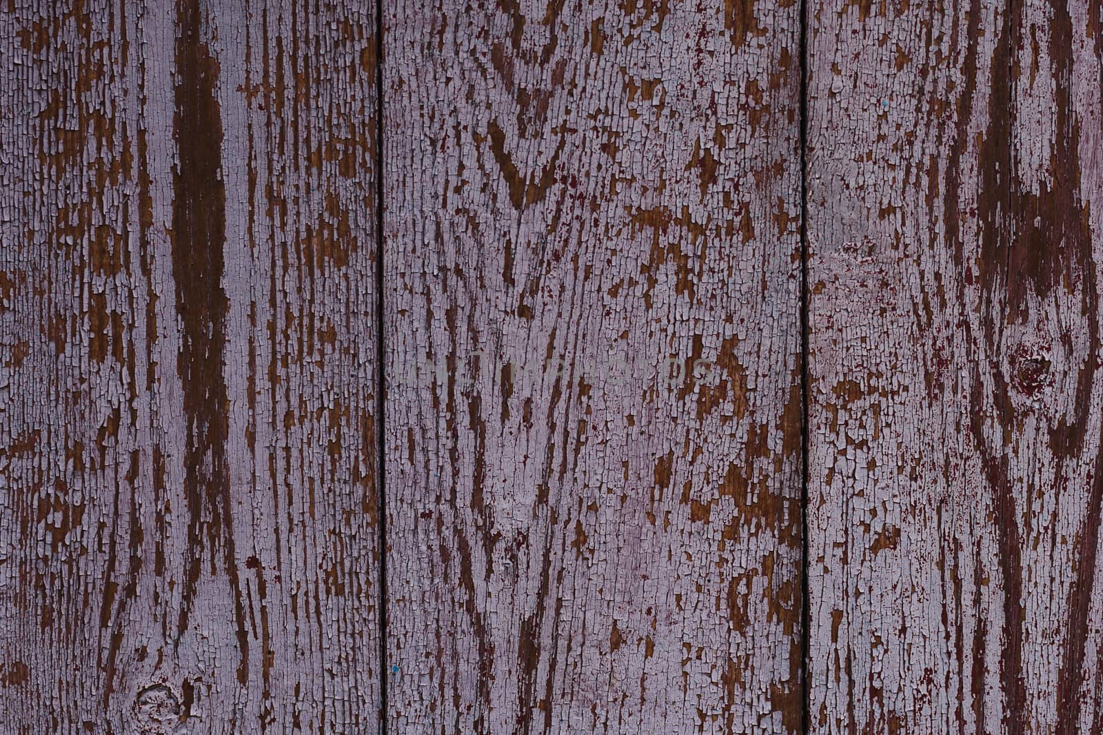 Old red wooden texured door surface closeup. Relief on surface. Stock photo of old wooden door pattern of aged boards with scratches. Red and gray colors on photo.