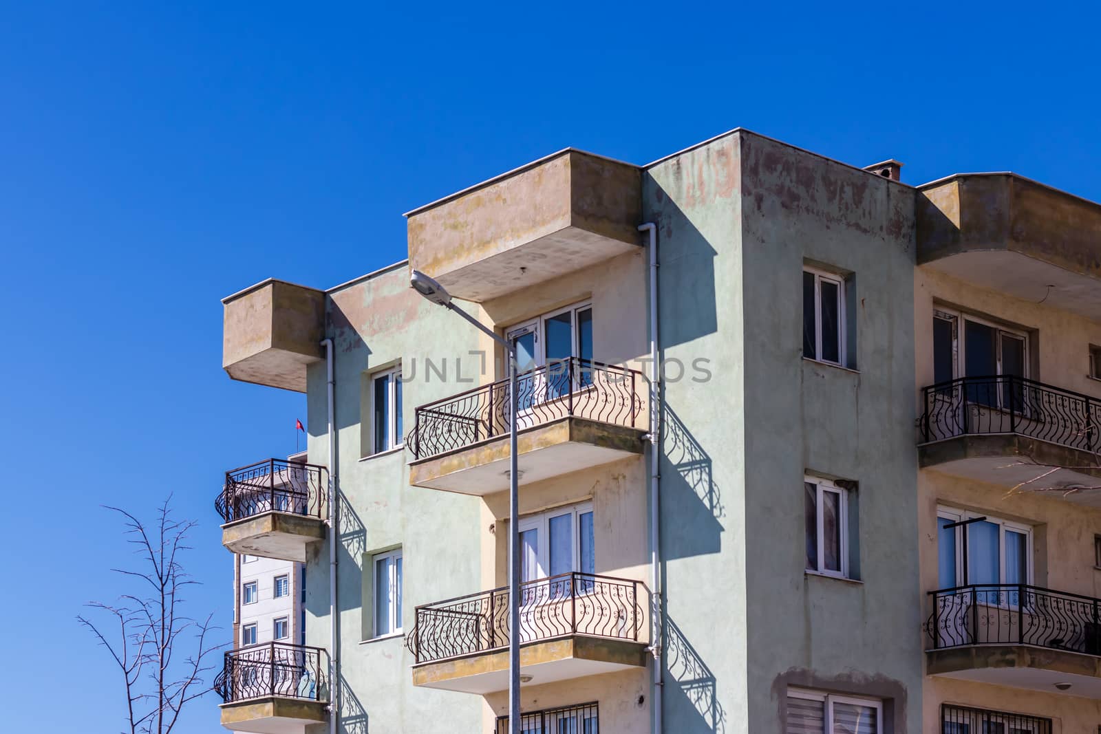 a corner shoot of a very old apartment with brown and white colors - clean blue sky as background. photo has taken at izmir/turkey.