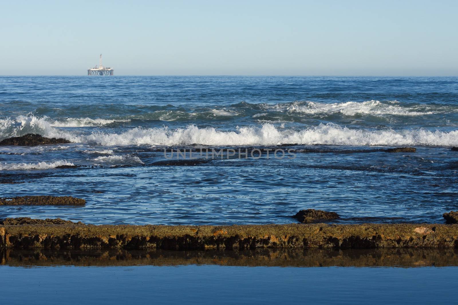 Seashore Tidal Pool And Rocks With Offshore Platform by jjvanginkel