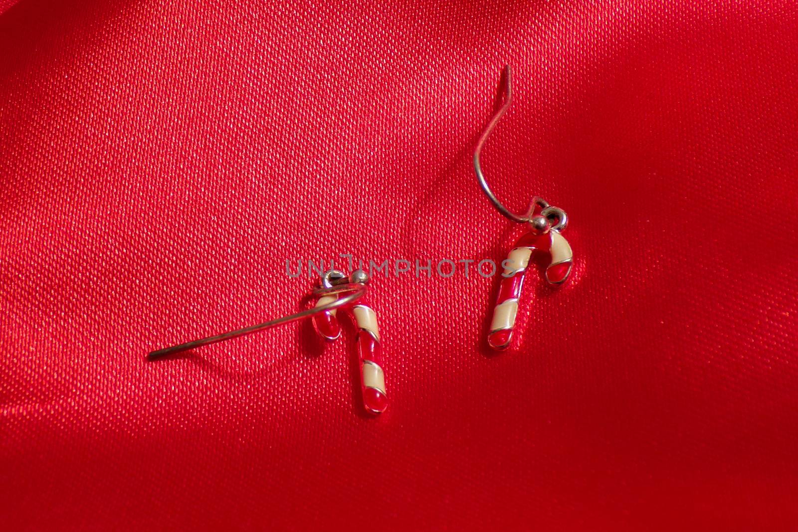 Earrings in the form of caramel sticks on a background of red fabric. Cute children's earrings.