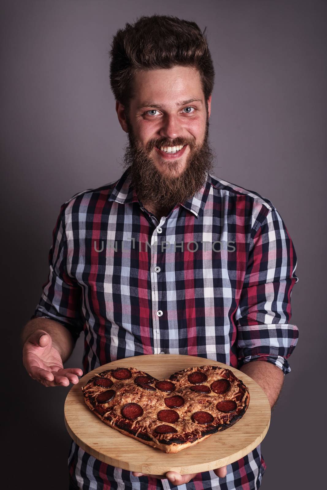 Happy smiling funny man gives burned heart shapes pizza
