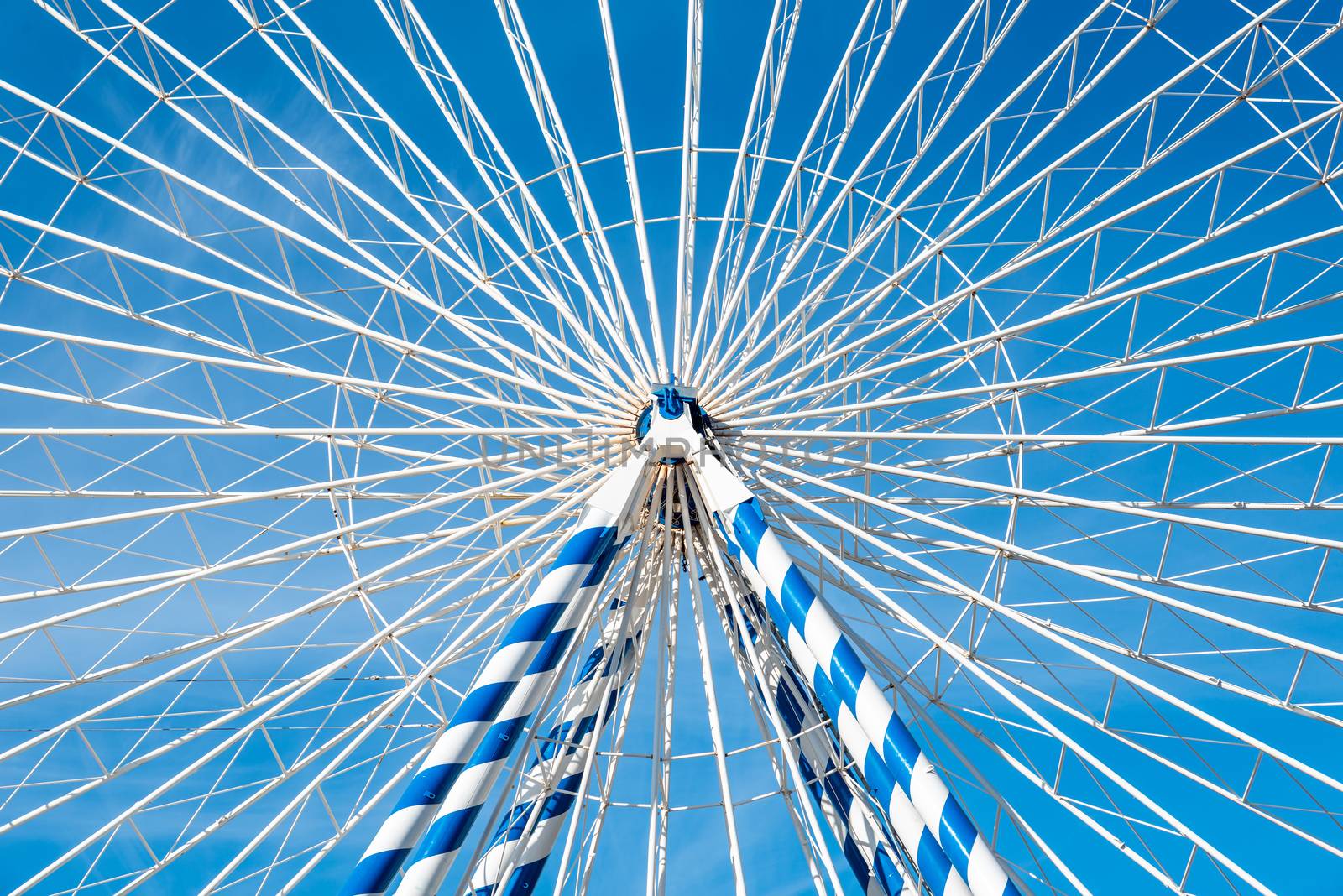 Detail of a white and blue ferris wheel with blue sky background