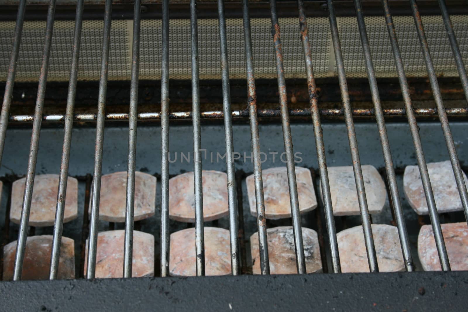 The grate of a gas grill with ceramic stones