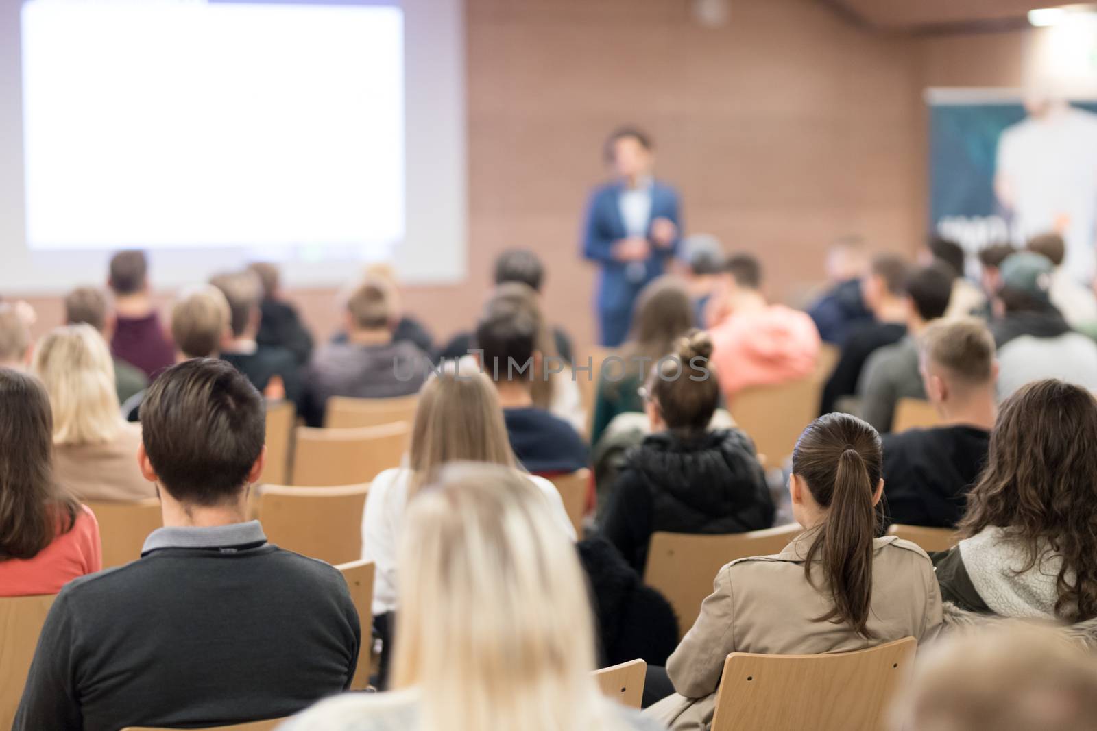 Speaker giving a talk in conference hall at business event. Audience at the conference hall. Business and Entrepreneurship concept. Focus on unrecognizable people in audience.