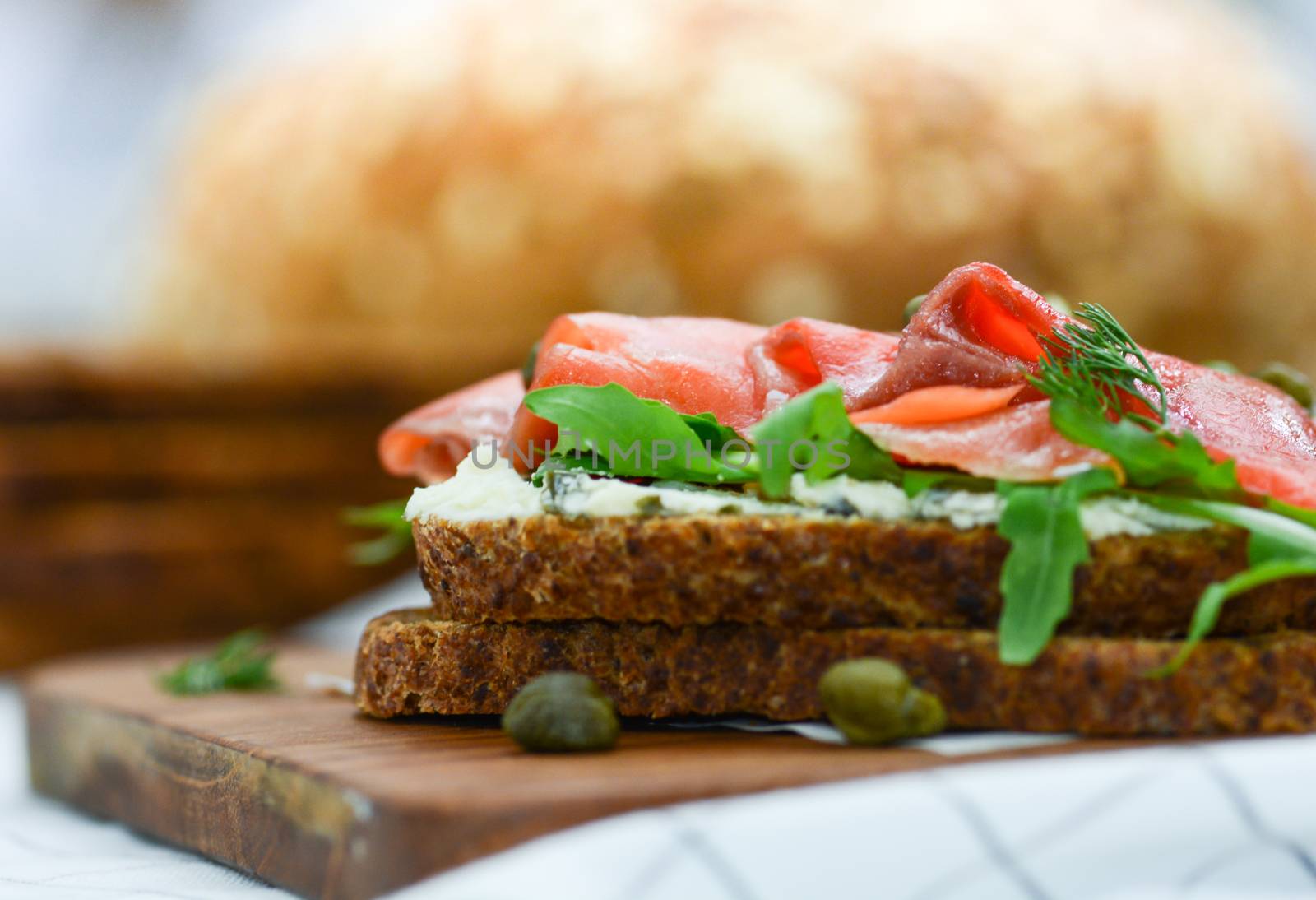 Smoked salmon sandwich with cheese, pistachio and salad leaves, brown breads