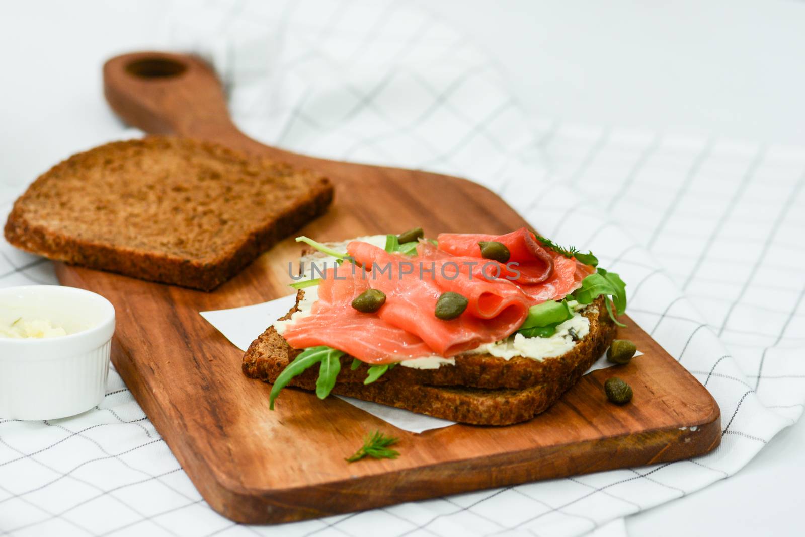 Smoked salmon sandwich with cheese, pistachio and salad leaves, brown breads