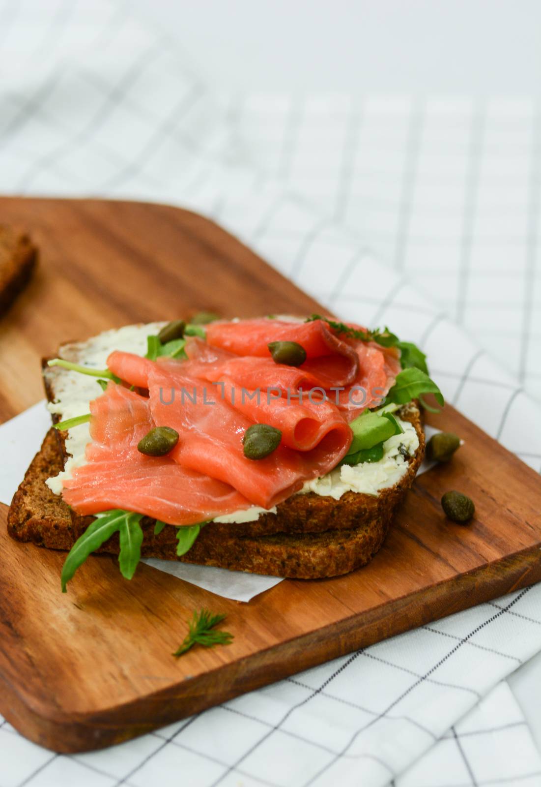 Smoked salmon sandwich with cheese, pistachio and salad leaves, brown breads