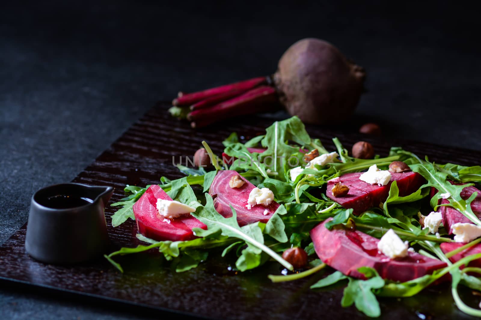 Fresh salad from beetroot, cheese and rocket salad on black wood background