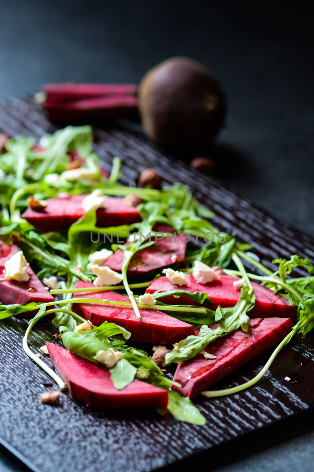 Fresh salad from beetroot, cheese and rocket salad on black wood background