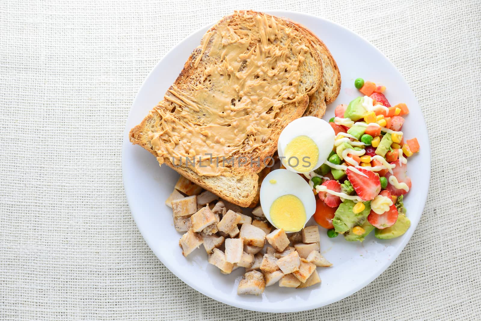 Modern style clean food, Peanut butter with bread, boiled egg, grilled chicken and avocado, strawberry, vegetable salad