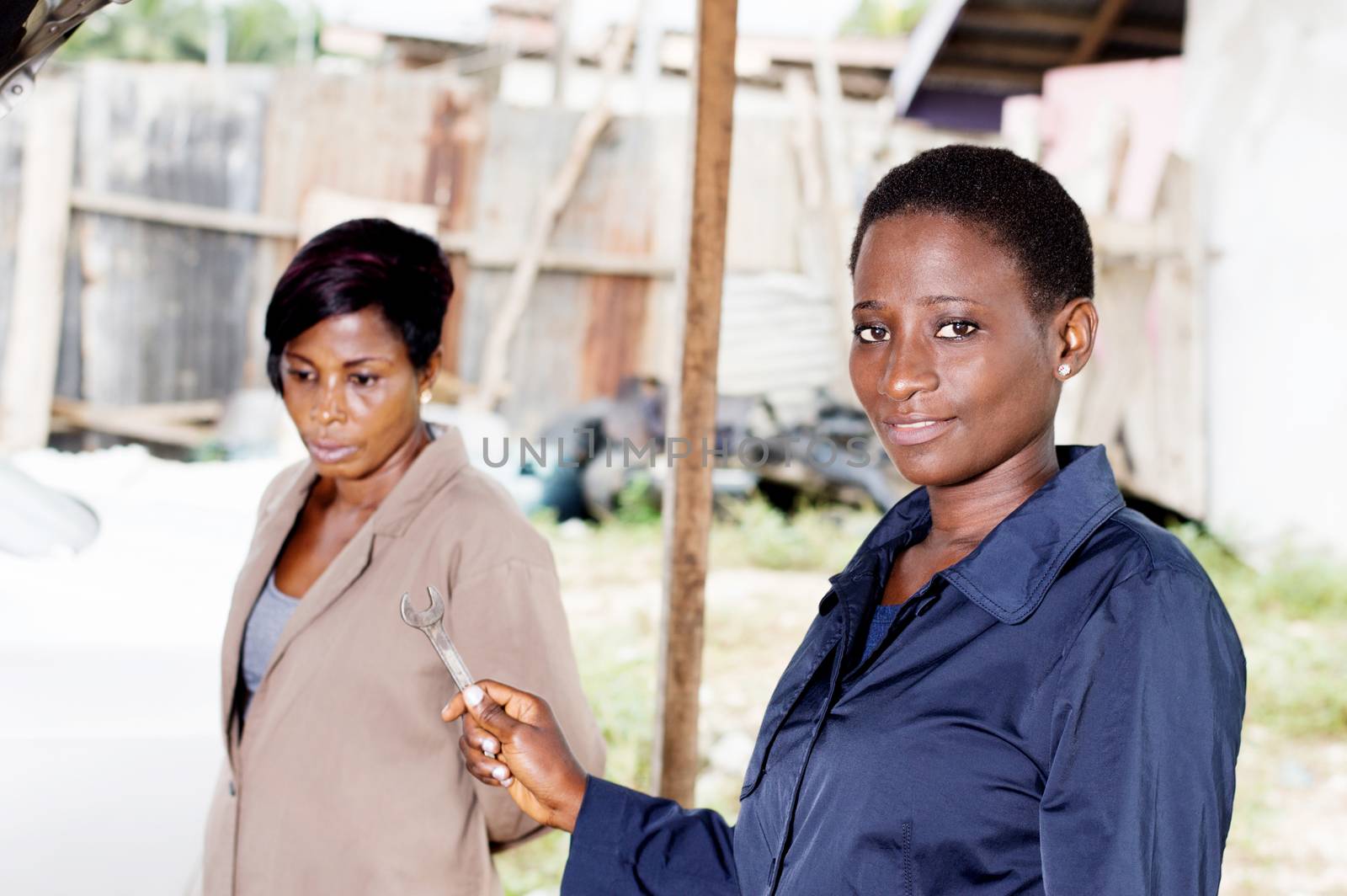 Young woman mechanic holds a key next to the owner of this car.