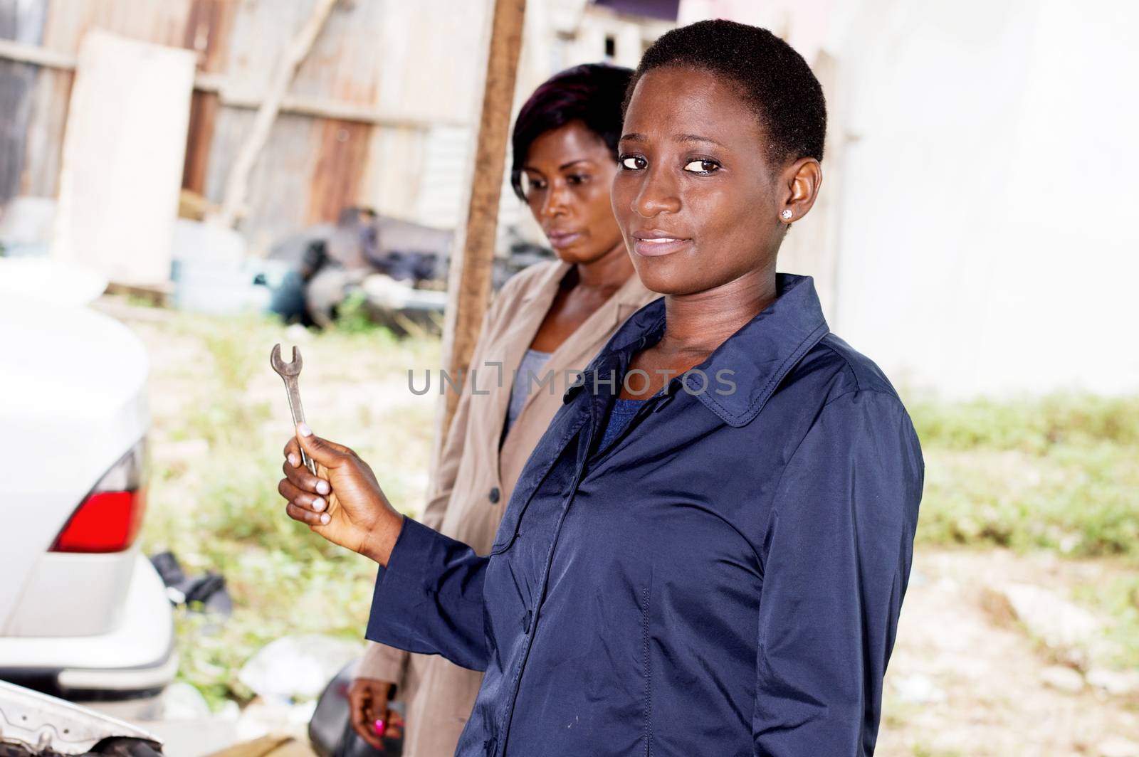 Young woman mechanic holds a key next to the owner of this car.