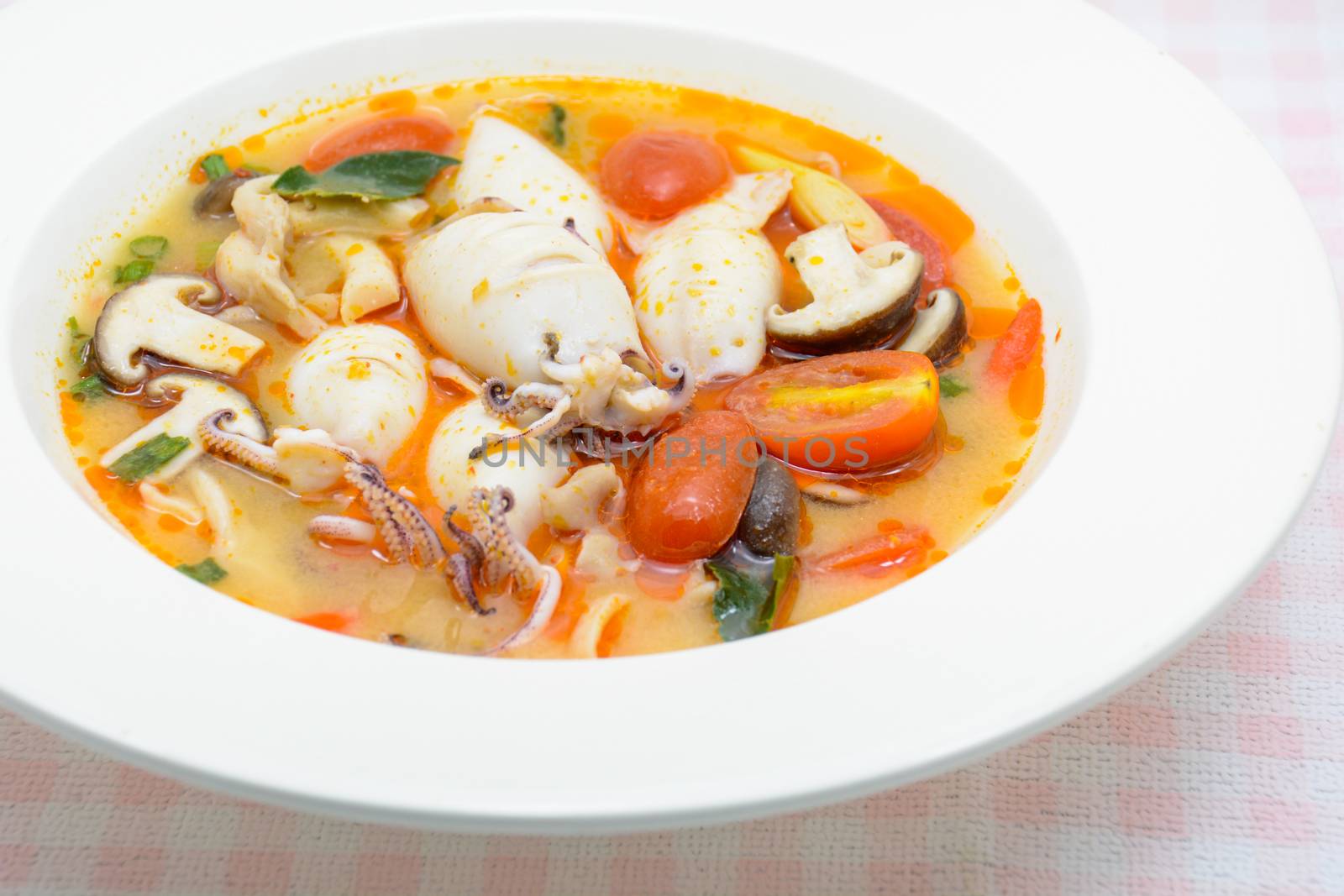 Squids and lemon grass spicy soup with mushrooms, tomatoes and herbs