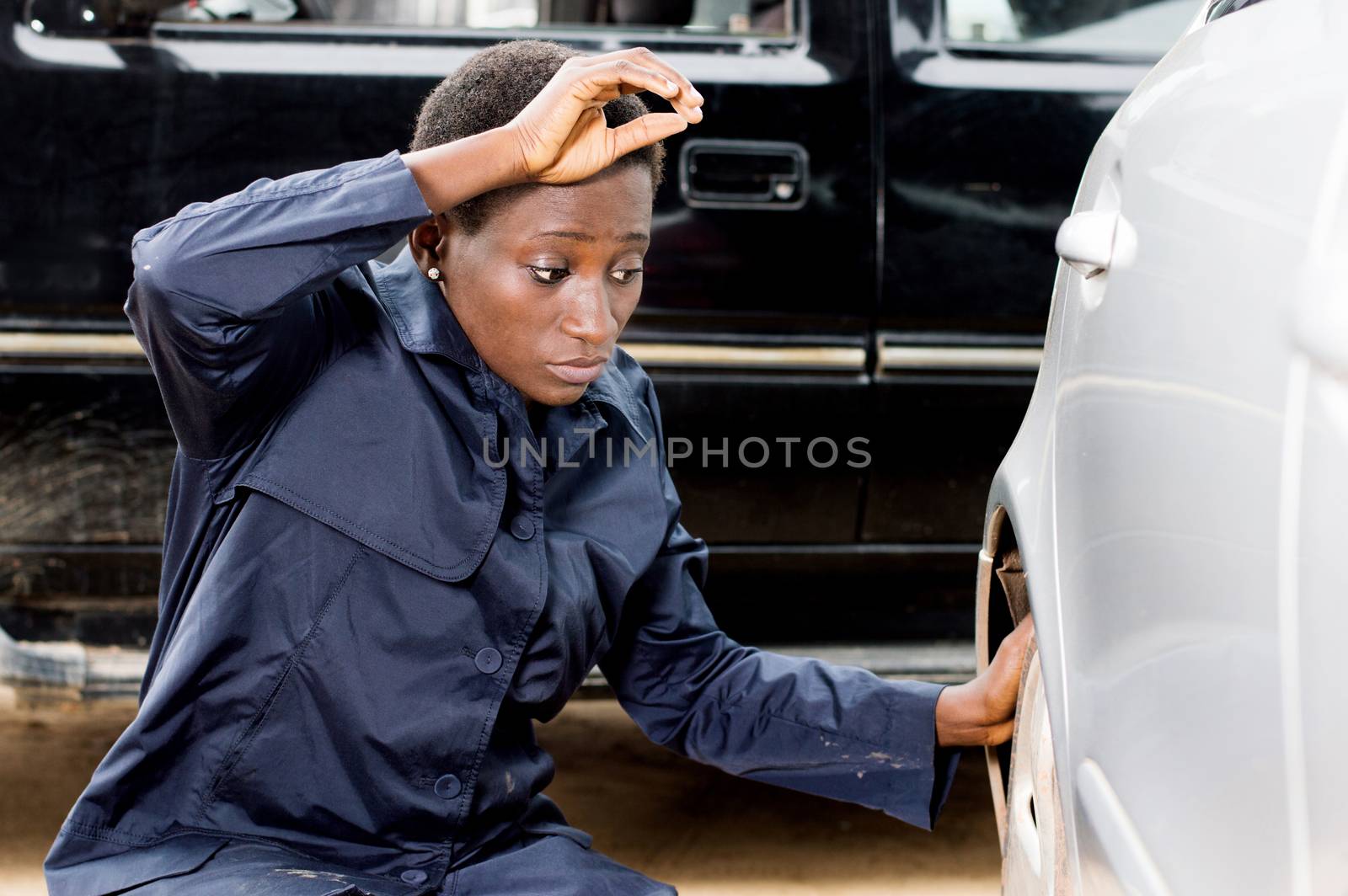 Closeup  of young woman mechanic changing the tire of a car in her garage.