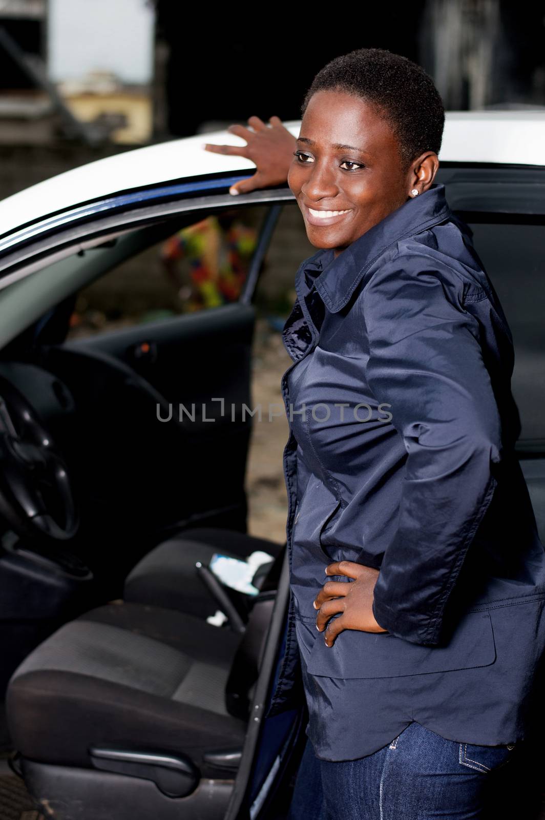 Young female mechanic standing beside this car is happy to settle the breakdown.