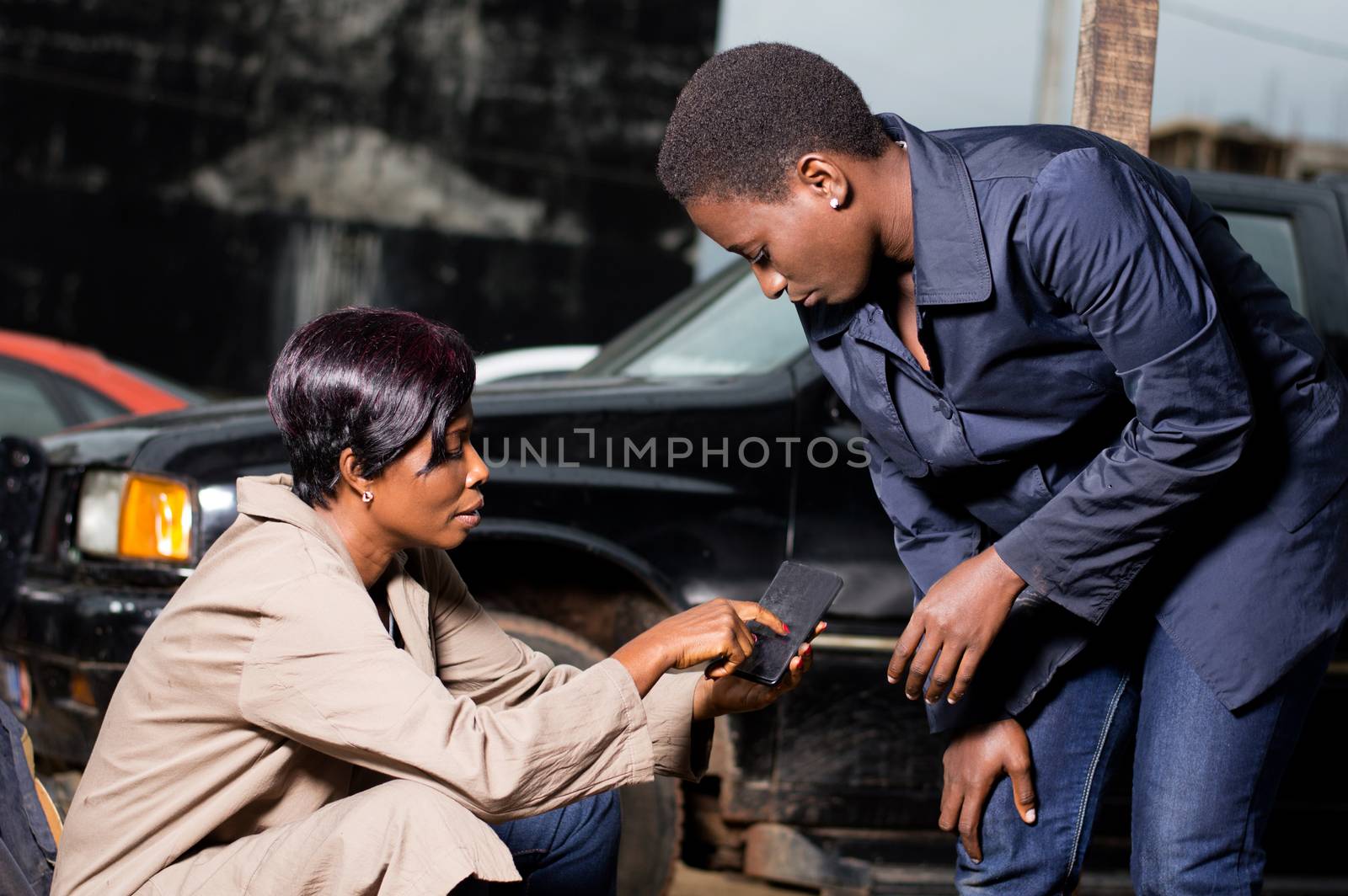 Young woman shows a room exam room she wants for her car to her mechanic in her phone.