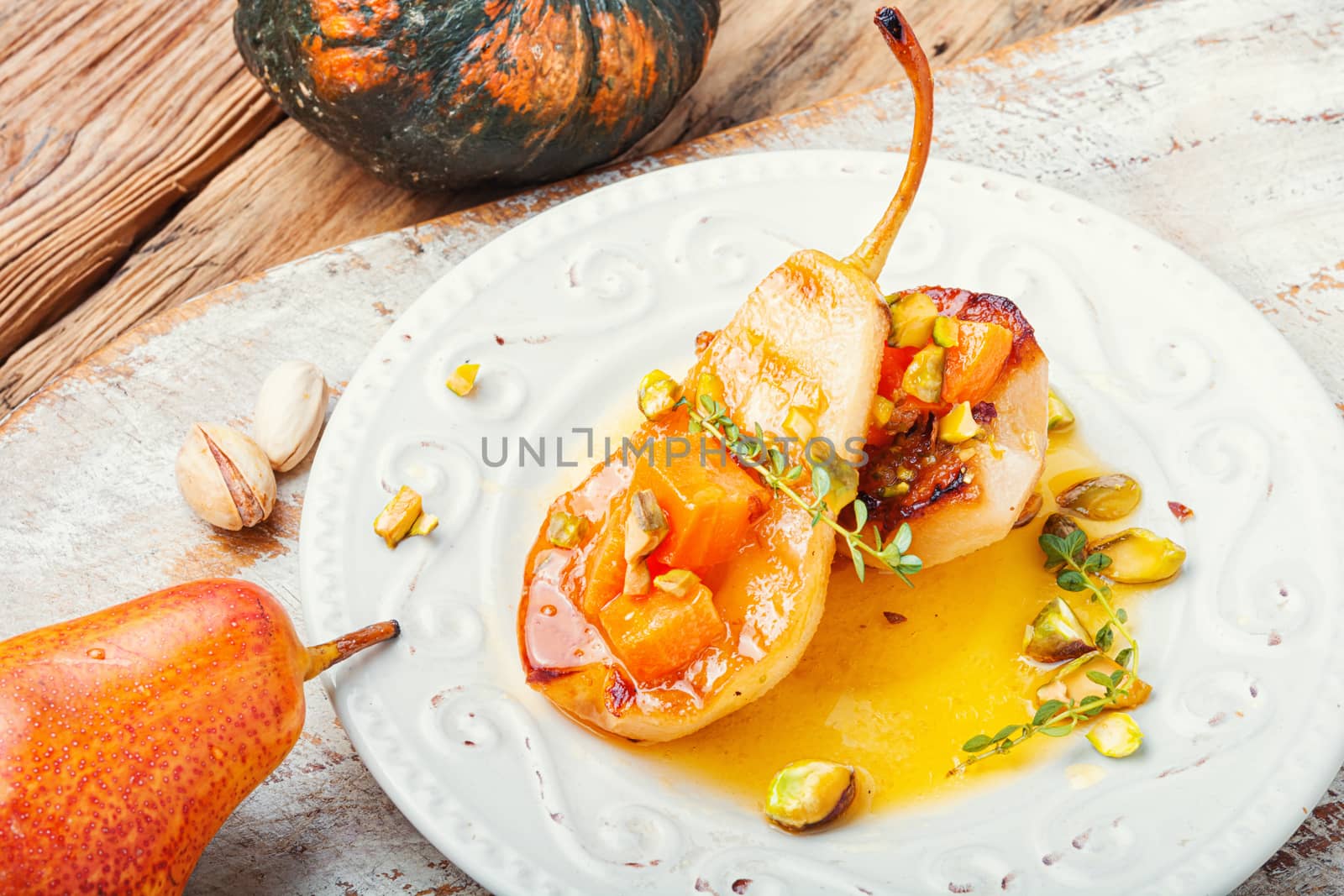 Stuffed pear pumpkin and pistachio.Autumn food.Baked pears with syrup on plate