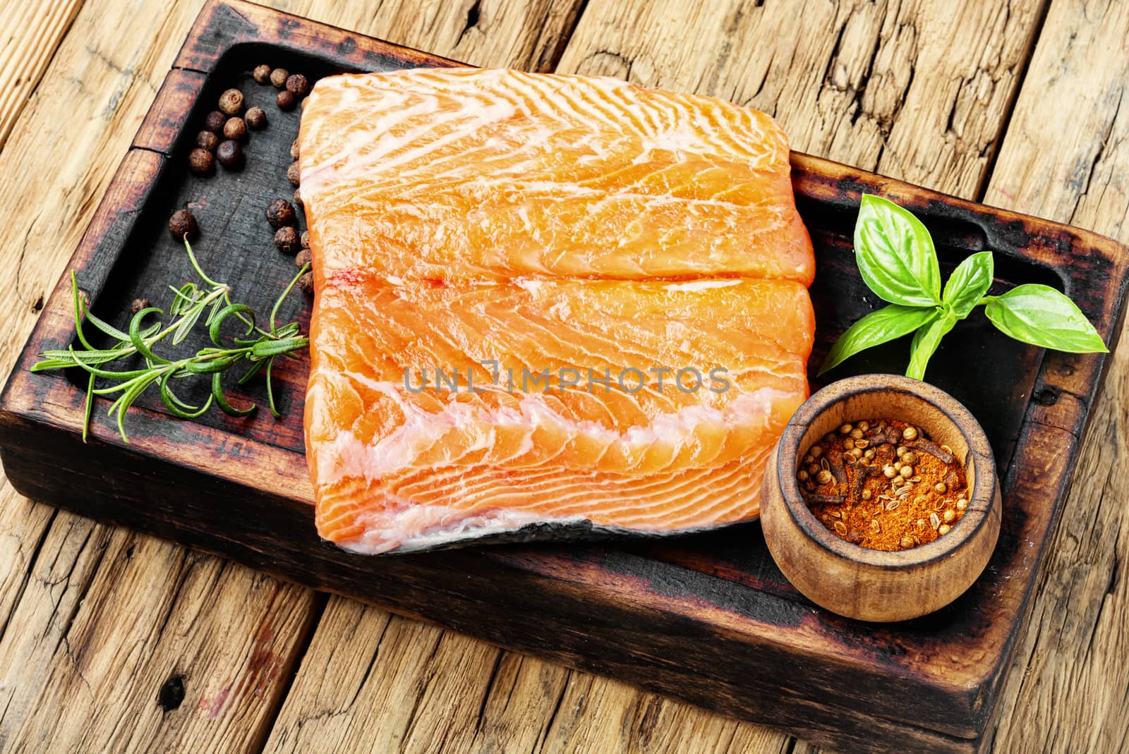 Raw salmon fillet with rosemary on wooden cutting board