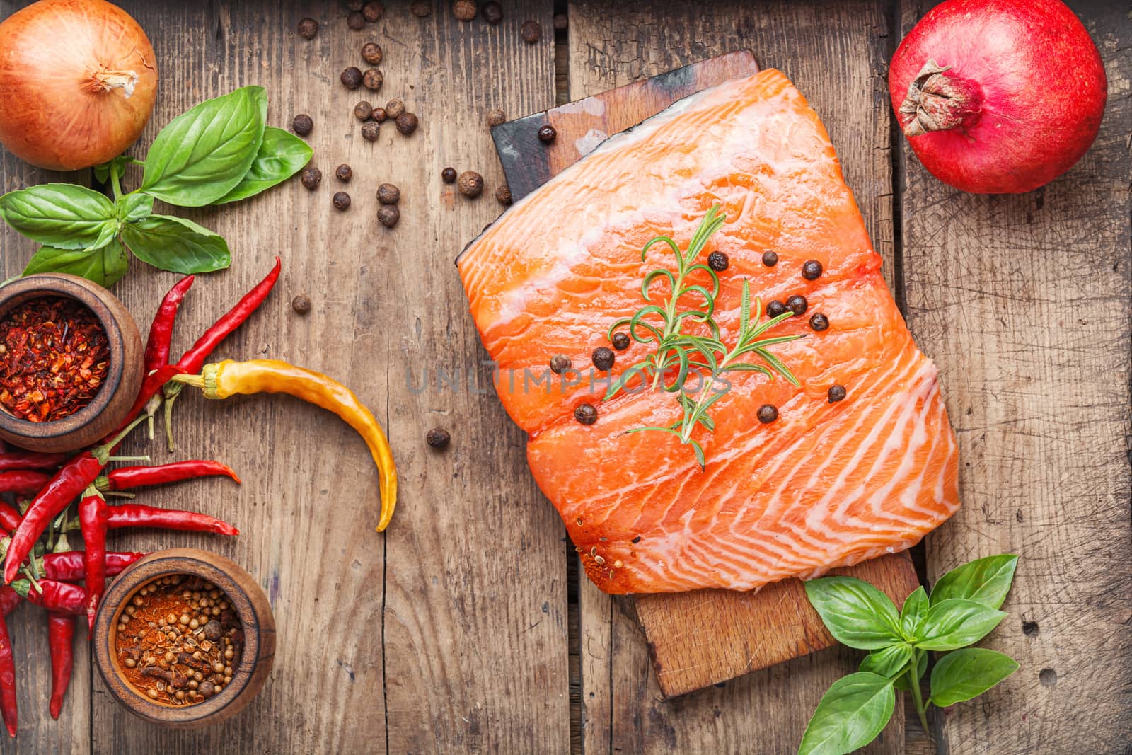 Raw salmon fillet with rosemary on wooden cutting board