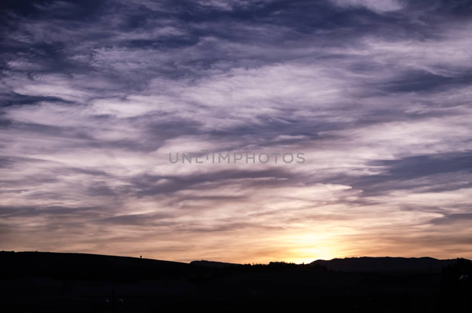 Blue, purple, orange and yellow beautifull sunset behind the hill of Zizur, Navarra, Spain