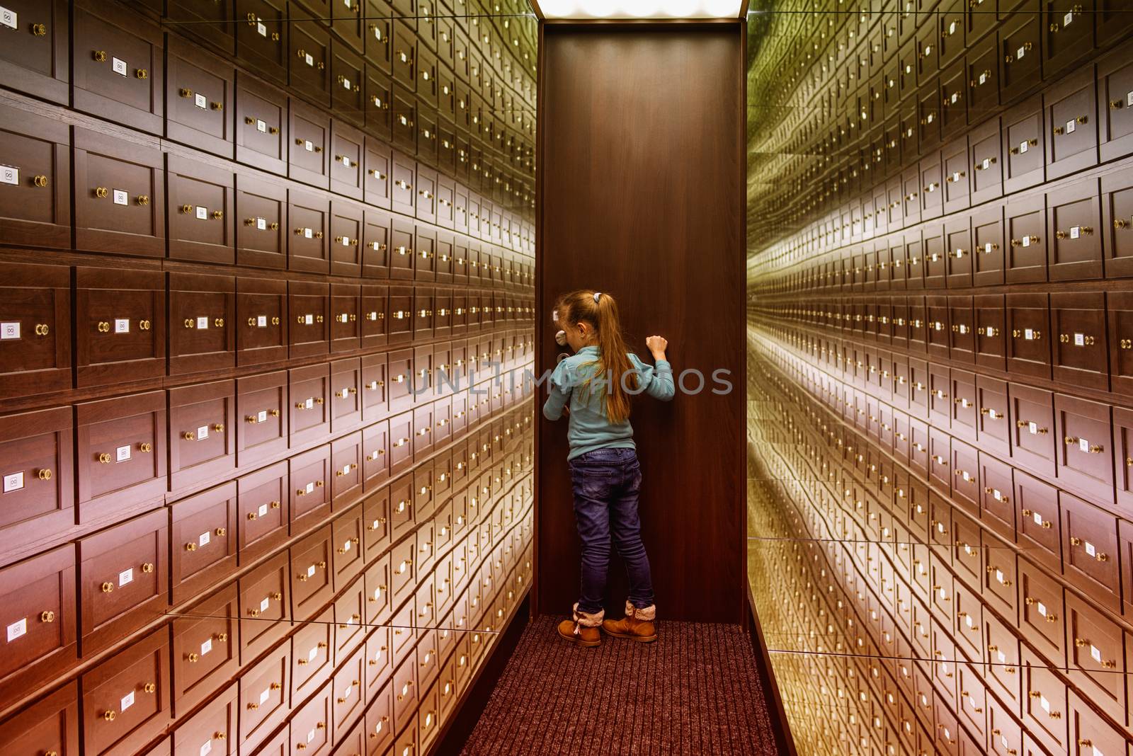 A little girl stands in the room of illusions. The safe room is a multi-colored room of illusions. Mirror room illusions. by nkooume