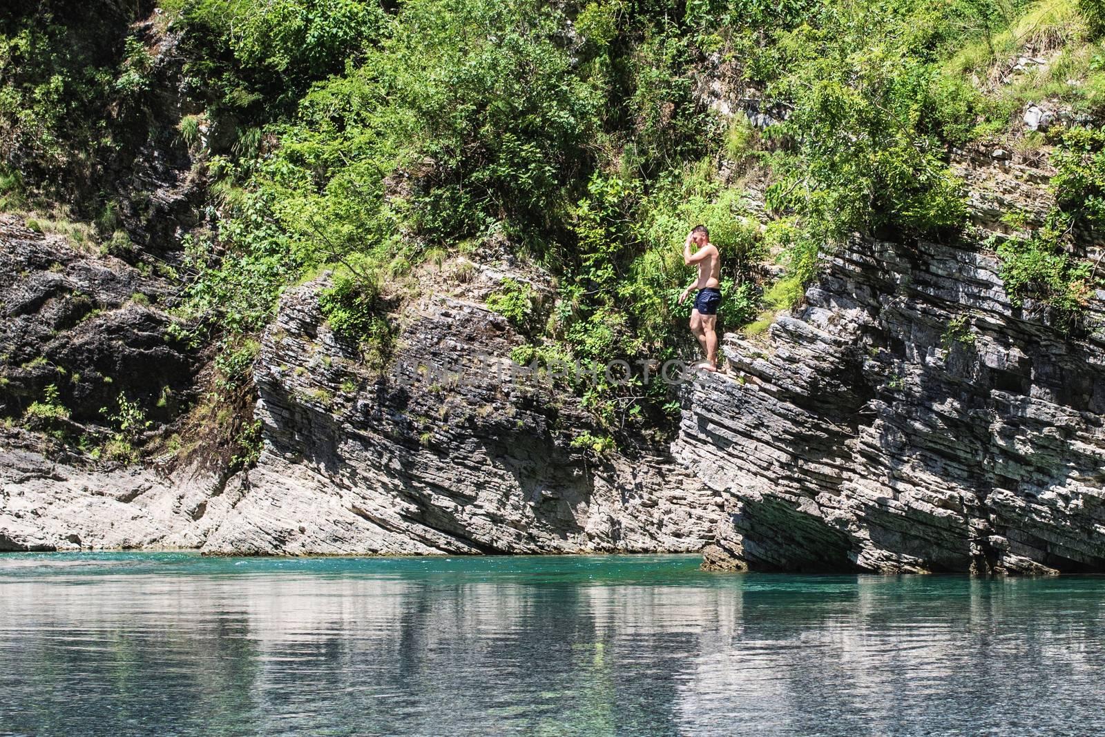 A man jumps from a cliff into a river. The abundance of nature. Albanian rivers.Cliff jumping into a mountain river .