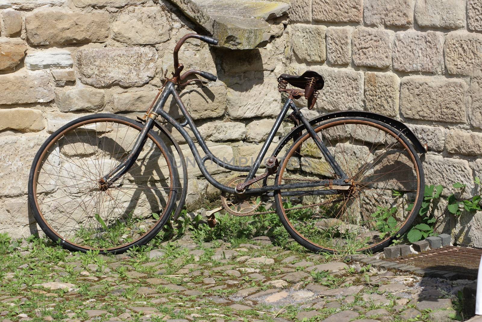 old rusty bicycle parked against a wall