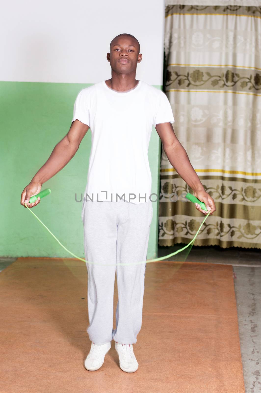 Young man trains by jumping rope in the gym.
